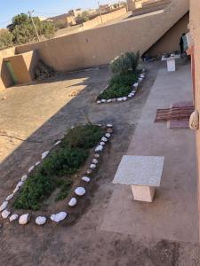 um jardim com pedras e um banco num passeio em DAR AMMAR em Merzouga