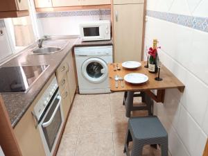 a small kitchen with a table and a washing machine at Apartamento Playa Cárabos in Melilla