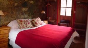 um quarto com uma cama grande e um cobertor vermelho em Lodge Rio Andino em Ushuaia