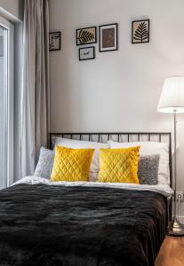 a bedroom with a black bed with yellow pillows at Apart D&K Free Parking Aleja Prymasa Tysiąclecia 83A in Warsaw