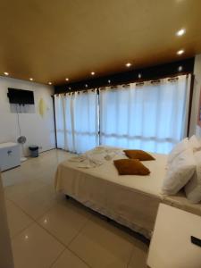1 dormitorio grande con 1 cama grande con cortinas en Pousada Beira Mar - Suítes Frente ao mar, en Torres