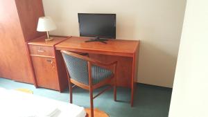 escritorio de madera con TV y silla en Pension Mesogios en Bad Doberan