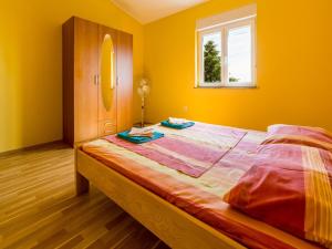 een slaapkamer met een bed met gele muren en een raam bij Apartment GORANKA in Crikvenica