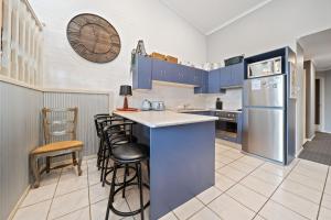 a kitchen with blue cabinets and a counter with stools at Acacia 2 Luxurious Holiday Townhouse in Jindabyne