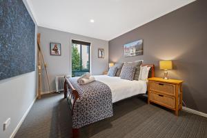 a bedroom with a bed and a table and a window at Acacia 2 Luxurious Holiday Townhouse in Jindabyne