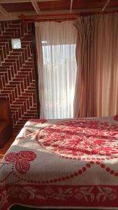 um quarto com uma cama com um cobertor vermelho e branco em Rancho los Alebrijes Zacatlan em Zacatlán