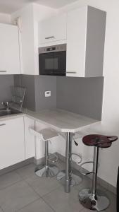 cocina blanca con mesa y microondas en Appartement Fodéré 2, en Niza
