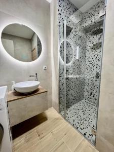 uma casa de banho com um chuveiro, um lavatório e um espelho. em The ONE Suites- with terrace in City Center em Kumanovo