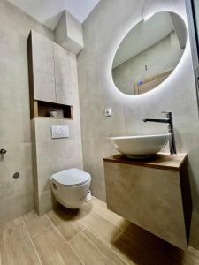 uma casa de banho com um lavatório, um WC e um espelho. em The ONE Suites- with terrace in City Center em Kumanovo