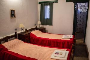two beds in a room with red and white sheets at El Progreso Molinos in Molinos