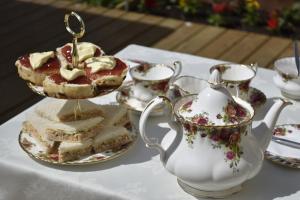 a table with a tea set with desserts and a tea pot at Flossies B and B in East Tisted