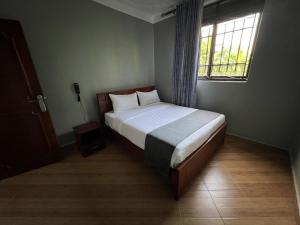 a bedroom with a bed and a window in a room at Orchid Suites, Kira in Bulindo