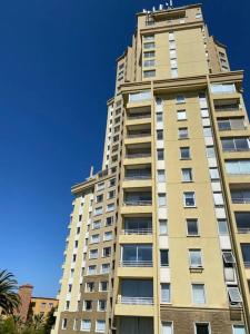 Precioso depto vista al mar Concon Condominio Tipo Resort 2 dormitorios في كونكون: مبنى شقق طويلة وذات سماء زرقاء في الخلفية