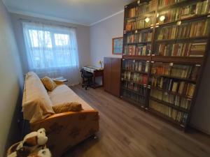 uma sala de estar com um sofá e prateleiras de livros com livros em Saknes apartamenti em Riga