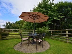 a table and chairs with an umbrella in a yard at 2 Bed in Widemouth Bay WOOWW in Poundstock