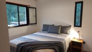 a bedroom with a bed and two windows at Ruca Reuemn in Mar del Plata