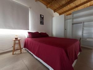 ein Schlafzimmer mit einem Bett mit einer roten Decke und einem Hocker in der Unterkunft Casa vacacional LUNA DE MAR in Santa Clara del Mar