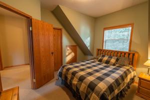 a bedroom with a bed with a checkered blanket at Nature's Getaway Mountain Resort- Cozy Bear Cabin in Nordegg