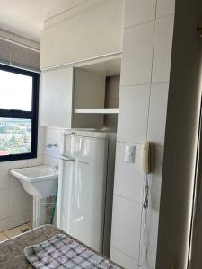 a white kitchen with a refrigerator and a sink at Flat completo no centro. in Palmas