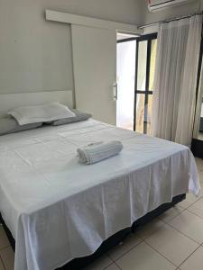 a white bed with a towel on top of it at Flat completo no centro. in Palmas