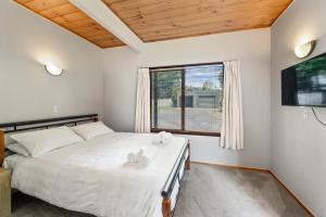 Schlafzimmer mit einem Bett und einem Fenster in der Unterkunft Kawaha on the Lake in Rotorua