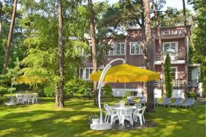 a table and chairs with a yellow umbrella in front of a building at Dom Wypoczynkowy Helunia in Jurata
