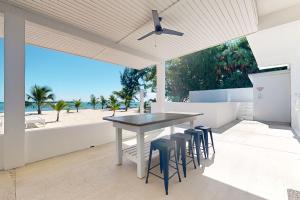 una sala da pranzo con tavolo e sgabelli di White Sands Beach House a Maya Beach
