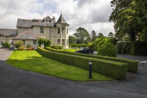 a house with a hedge in front of a driveway at Plas Meirion Apartment 3 in Trefriw