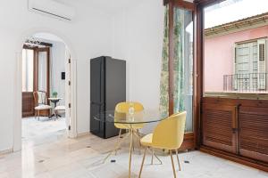 a dining room with a glass table and yellow chairs at Trinidad Grund Centro in Málaga