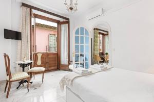 a white bedroom with a bed and a table and chairs at Trinidad Grund Centro in Málaga