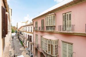 an alley in an old town with pink buildings at Trinidad Grund Centro in Málaga