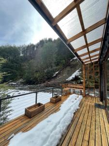 a wooden deck with snow on the ground at Cabañas Los Huemules in Malalcahuello