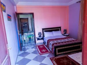 a bedroom with a bed and a pink wall at راحة المسافر، Rahat al moussafir in Azilal