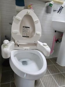 a bathroom with a toilet with a sign on the seat at Donghae sea hill House in Yŏngdŏk