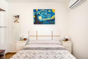 1 dormitorio con 1 cama y una pintura en la pared en El Remanso, en Sevilla