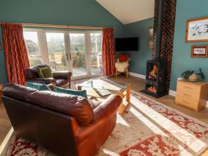 a living room with a leather couch and a fireplace at Summerseats Cottage in Alnwick