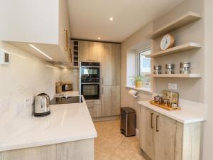 a large kitchen with white counter tops and appliances at Summerseats Cottage in Alnwick