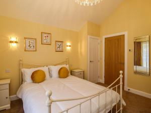 a bedroom with a white bed with yellow walls at Summerseats Cottage in Alnwick