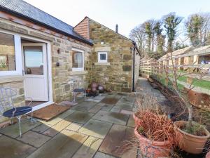 a stone house with a patio with chairs and plants at Summerseats Cottage in Alnwick
