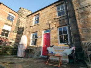 a red door on a brick building with a chair at Rose Lea in Saltburn-by-the-Sea