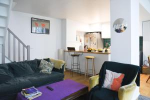a living room with a couch and a kitchen at Spacious duplex - near park in Paris