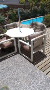 une table et des chaises blanches sur une terrasse avec piscine dans l'établissement Casa en Papudo, à Petorca
