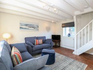 a living room with a blue couch and a tv at Spring Cottage in Norwich