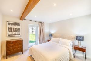 a white bedroom with a bed and a window at Ysgubor Maen Y Bardd in Conwy