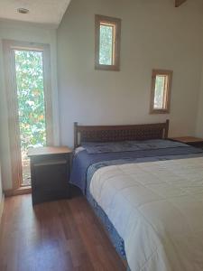 1 dormitorio con 1 cama y 2 ventanas en Ruca lemu lodge, en San Antonio