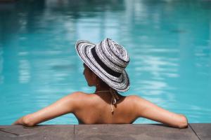 a woman wearing a hat sitting next to a swimming pool at Holiday Inn Resort Bali Canggu by IHG in Canggu