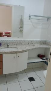 een witte keuken met een wastafel en een spiegel bij Ap Serra Park in Rio Quente