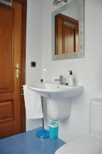 Baño blanco con lavabo y espejo en Alojamiento Santa Maria III, en Milladoiro