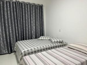two beds in a room with black curtains at AP 2 Quartos 6 Pessoas Luxo 200mt Axé Moi in Porto Seguro