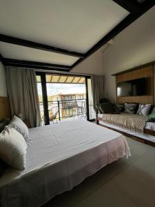 um quarto com uma grande cama branca e uma varanda em Lar aconchegante Praia do Forte na Praia do Forte
